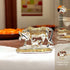 Decorative golden and silver cow figurine on a table with text highlighting features.